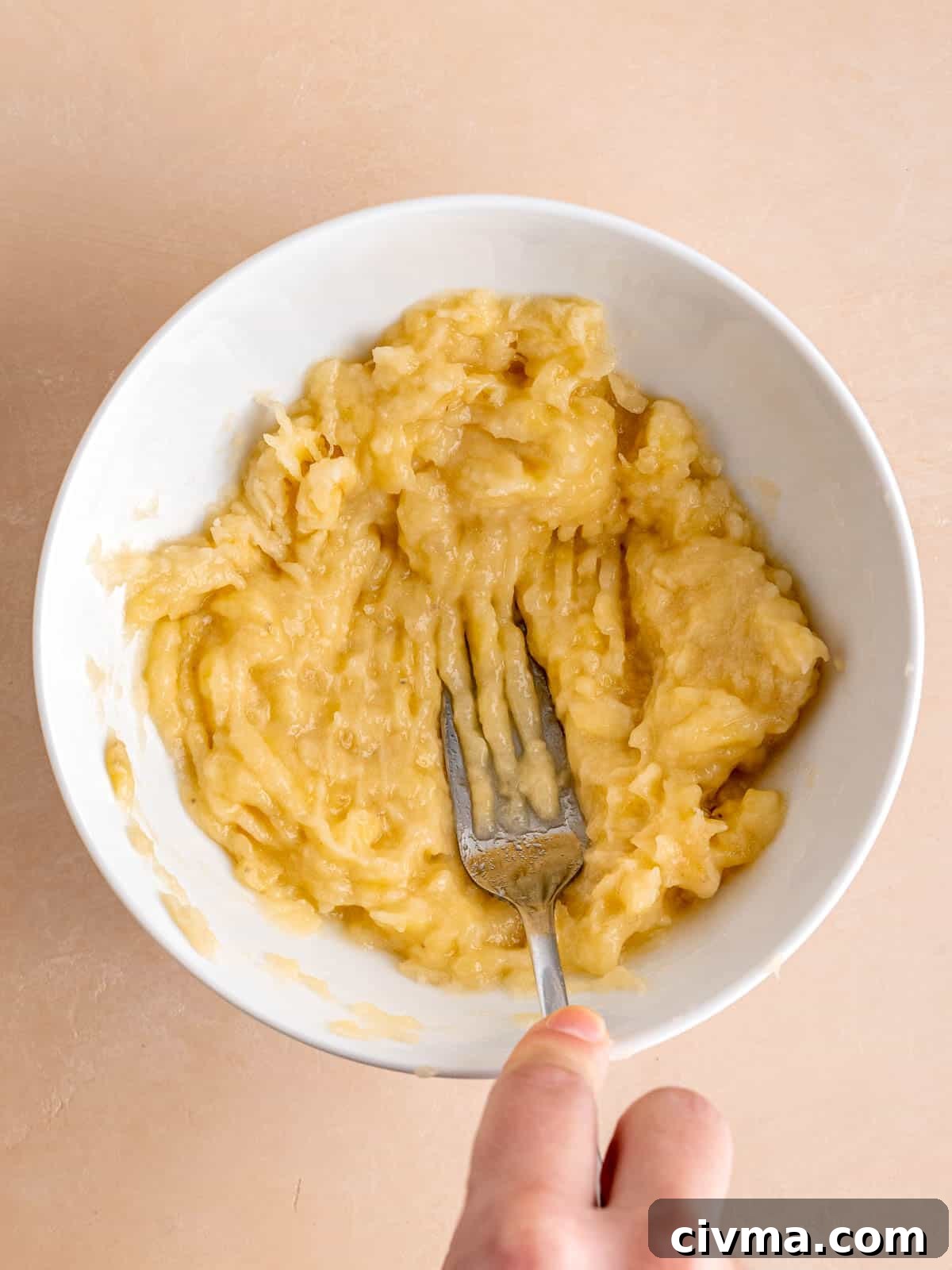 Mashing overripe bananas in a bowl with a fork.