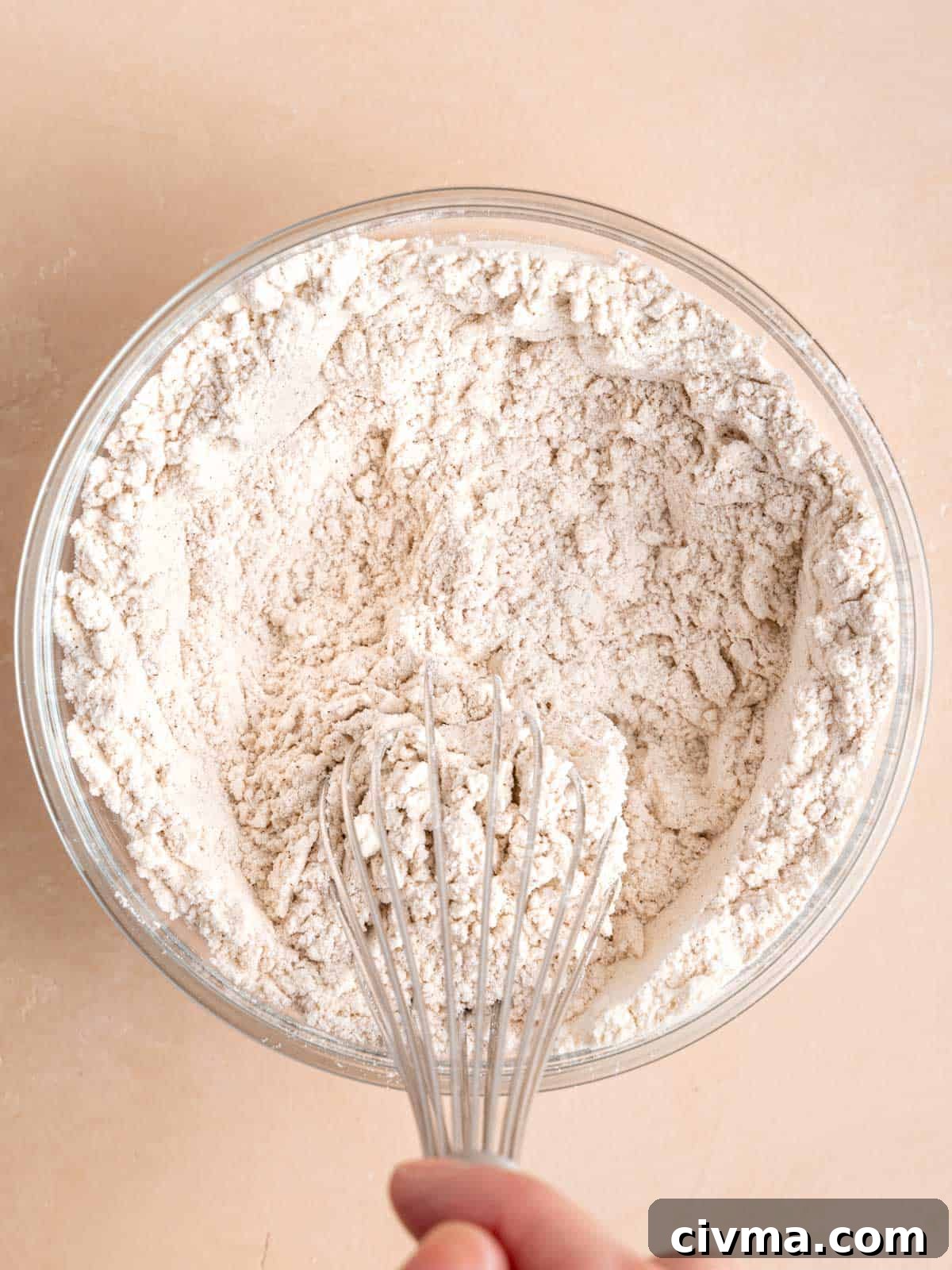 Whisking flour, baking soda, salt, and cinnamon in a bowl.