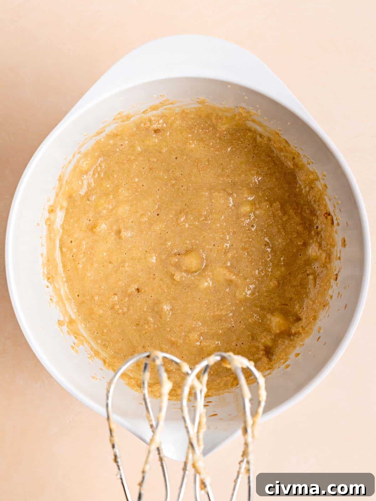 Butter, brown sugar, egg, vanilla extract, sour cream, and bananas mixed in a bowl.