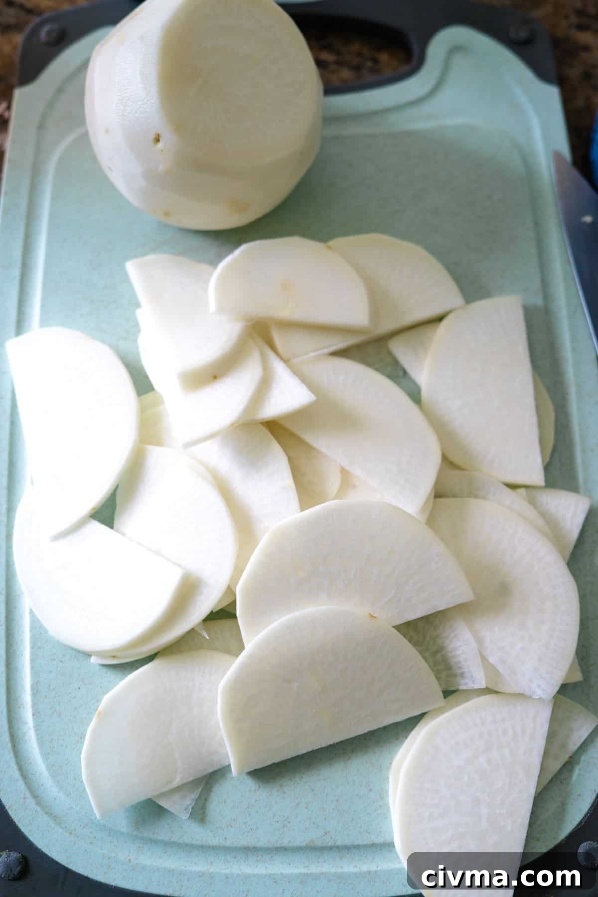 Sliced onions on a cutting board for turnip gratin.