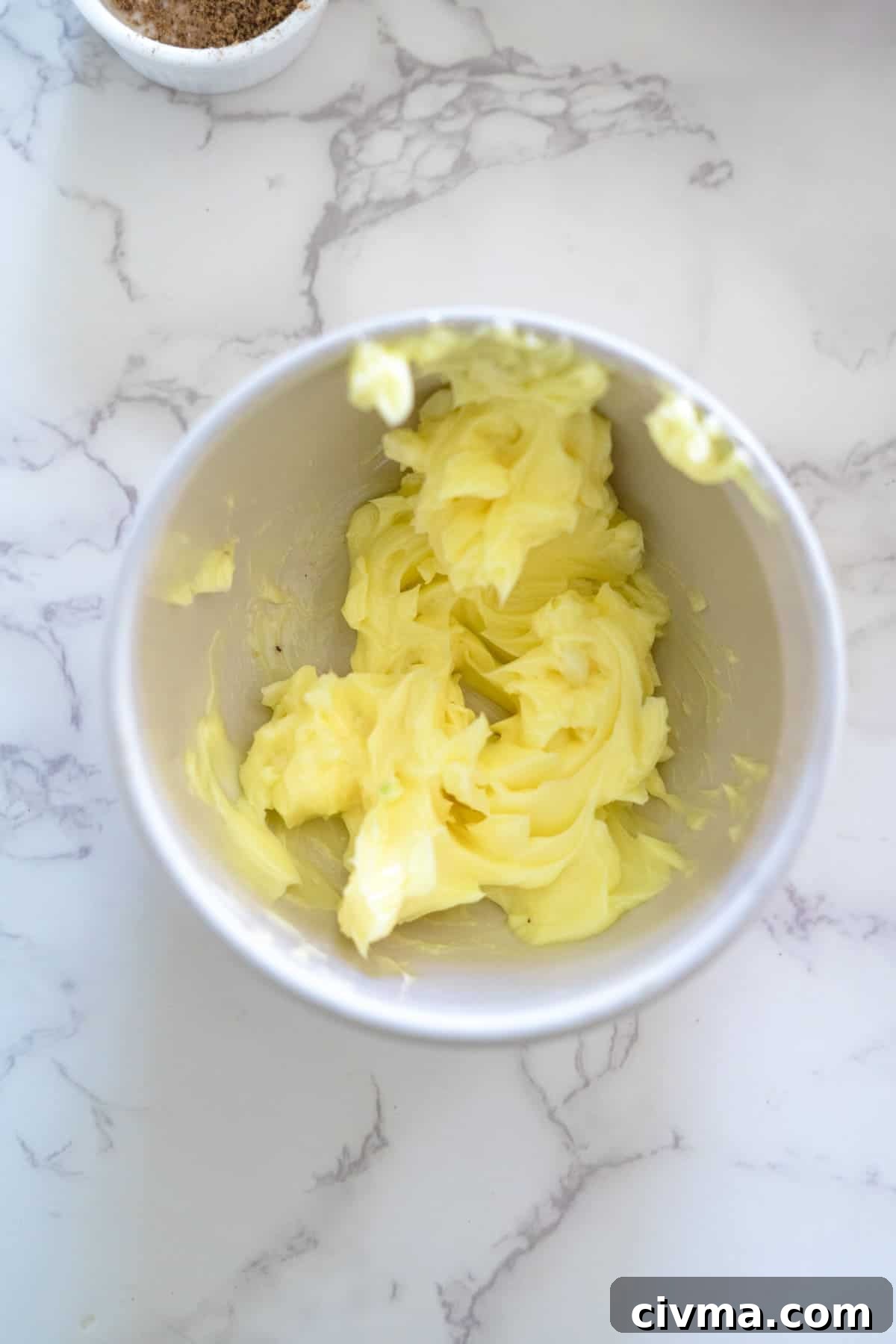 Butter in a bowl next to turnip gratin ingredients.