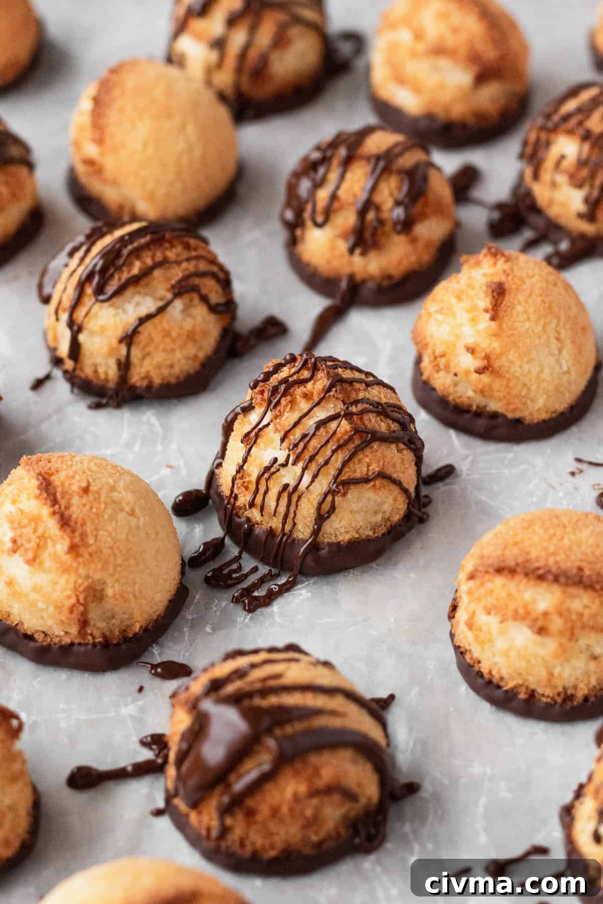 Plain and chocolate drizzled vegan coconut macaroons on a white surface.