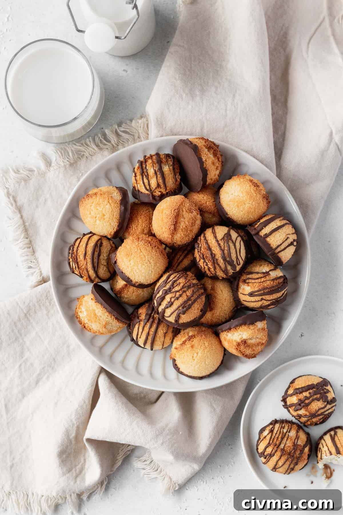 Overhead shot of plain and chocolate drizzled coconut macaroons on a plate.