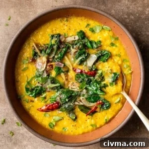 Dal palak in maroon bowl on a table.