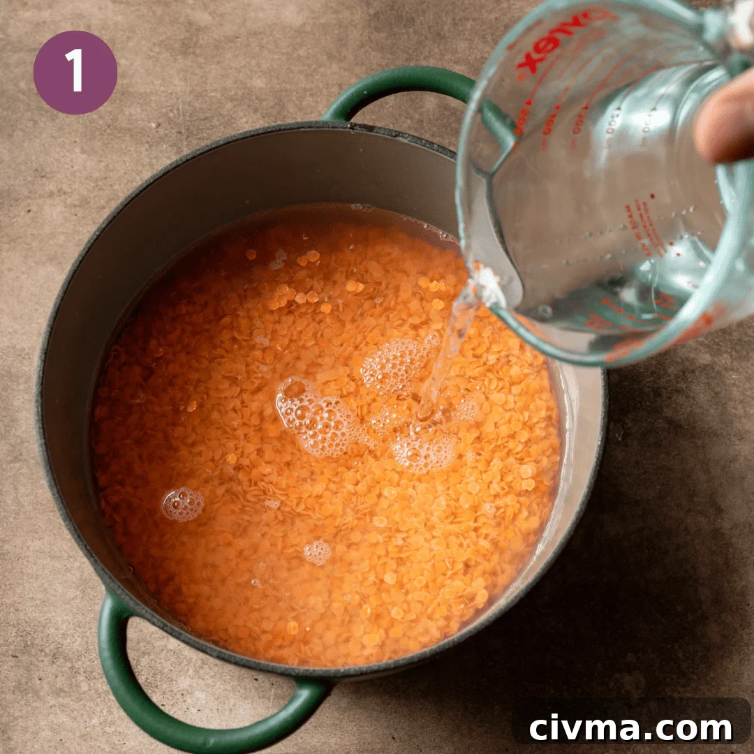 Person pouring water over lentils in a large pot.