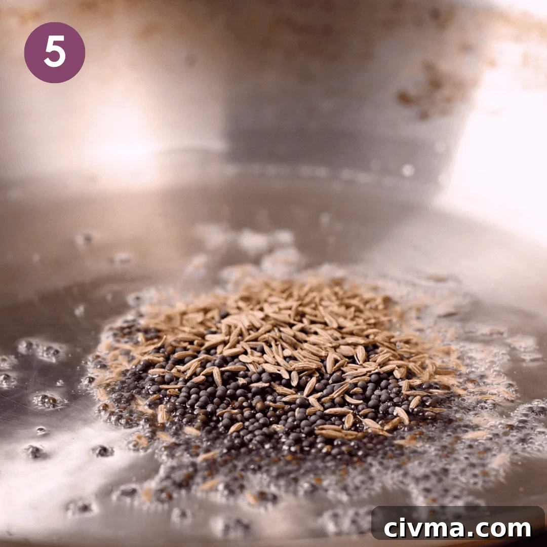 cumin and mustard seeds cooking in the oil on a saucepan.