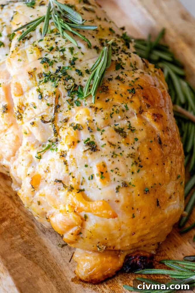 A roasted turkey on a cutting board with sprigs of rosemary. Oven Baked Turkey Breast.