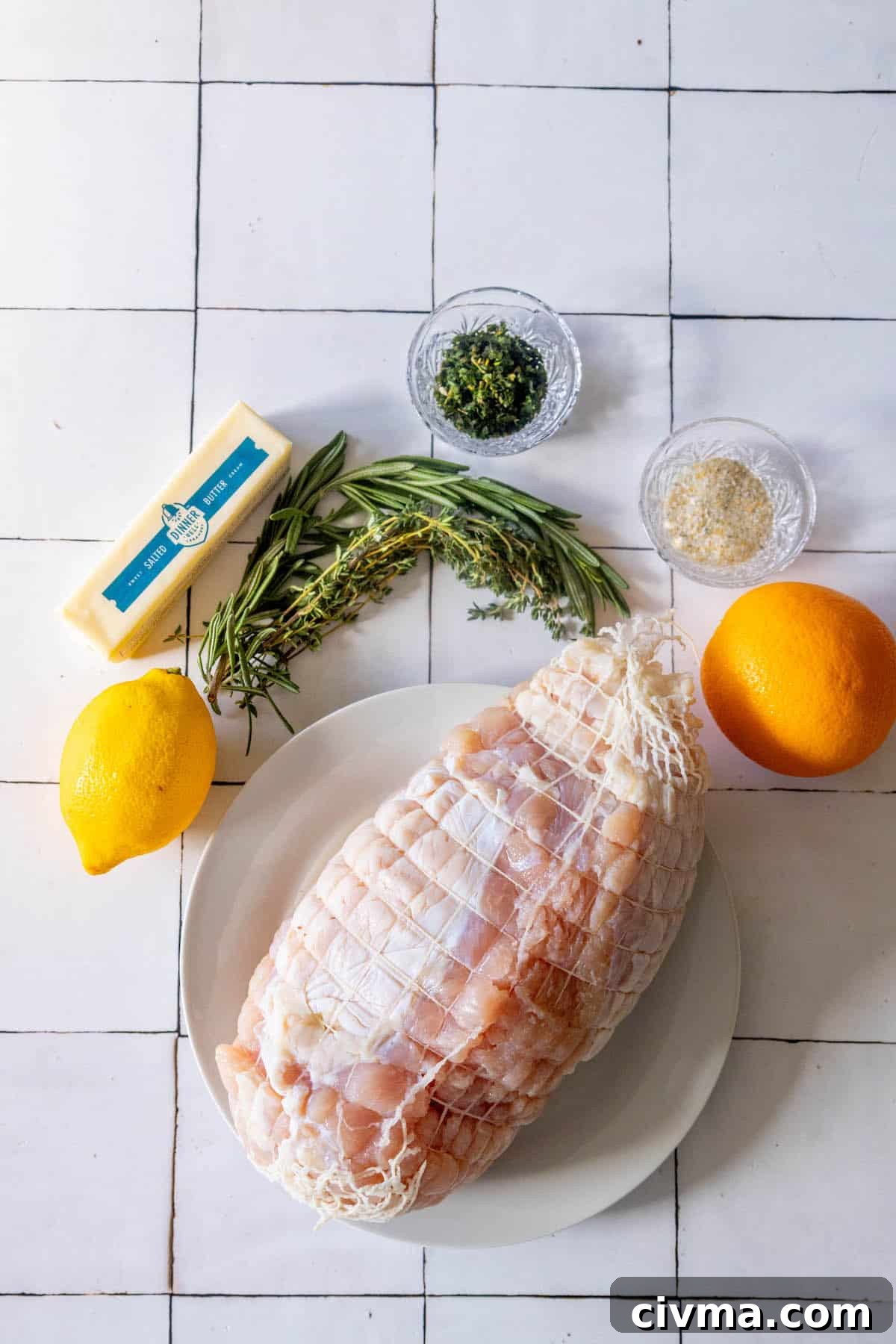 A plate with herbs, lemons, and baked turkey breast on it.