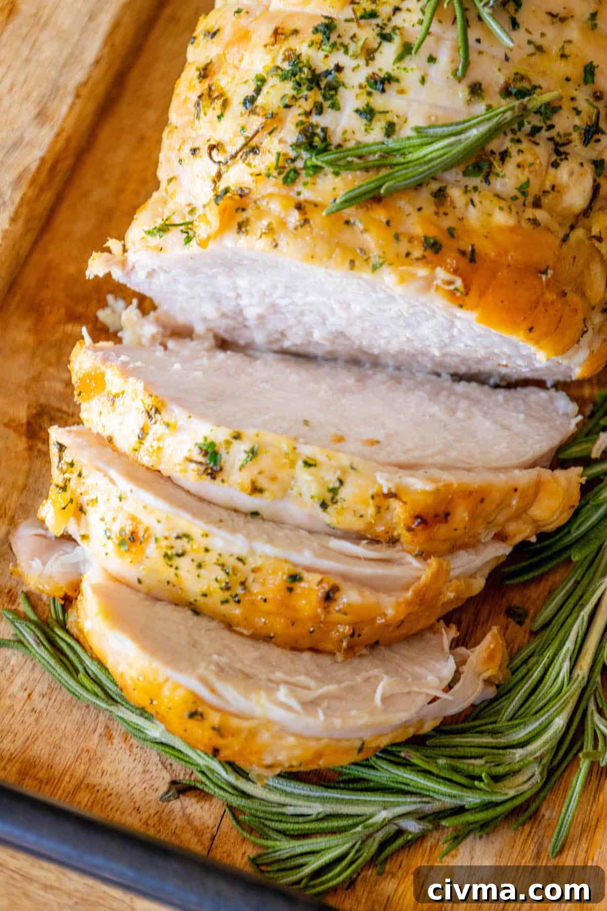 Sliced turkey with rosemary on a cutting board.