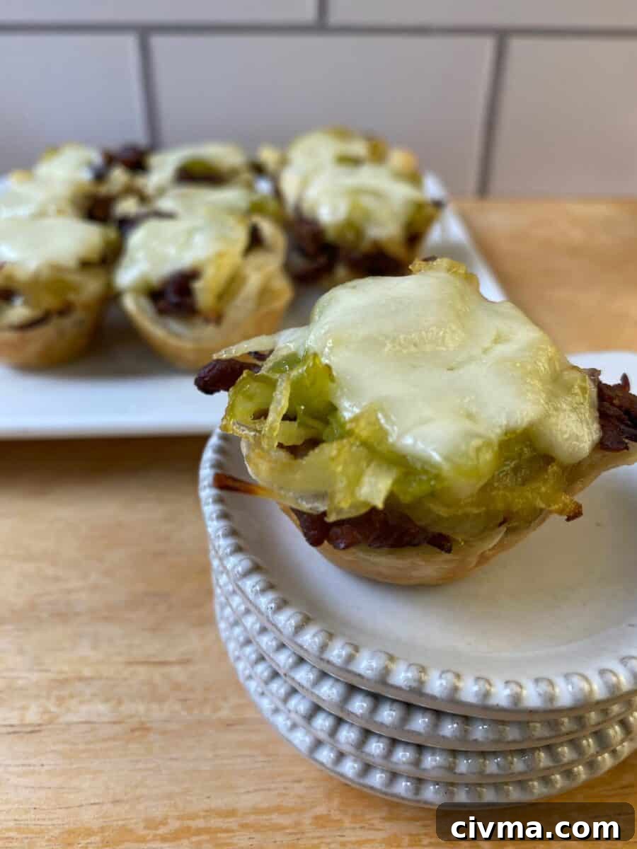 Philly Cheesesteak Bites Recipe 2 Philly Cheesesteak bite on a small stack of dishes with the serving plate in the background.
