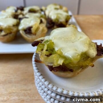 Philly Cheesesteak Bites Recipe 12 Philly Cheesesteak bite on a small stack of dishes with the serving plate in the background.