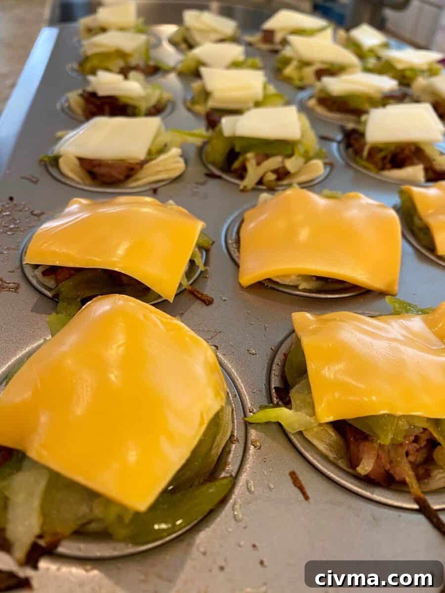 Philly Cheesesteak Bites Recipe 4 Mini Philly Cheesesteaks in a mini-muffin pan with melted cheese on top of each one.