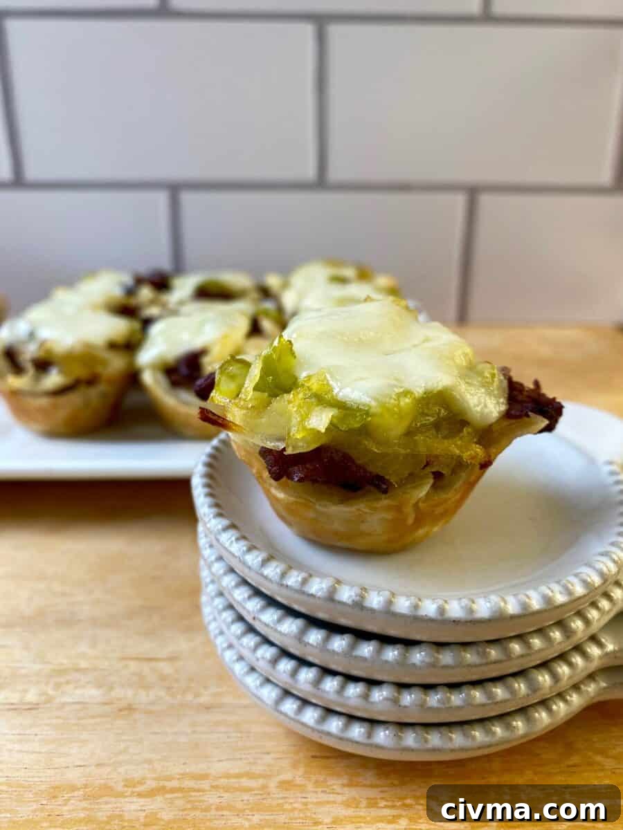 Philly Cheesesteak Bites Recipe 5 Philly Cheesesteak Bite on a small stack of dishes with the serving plate in the background.