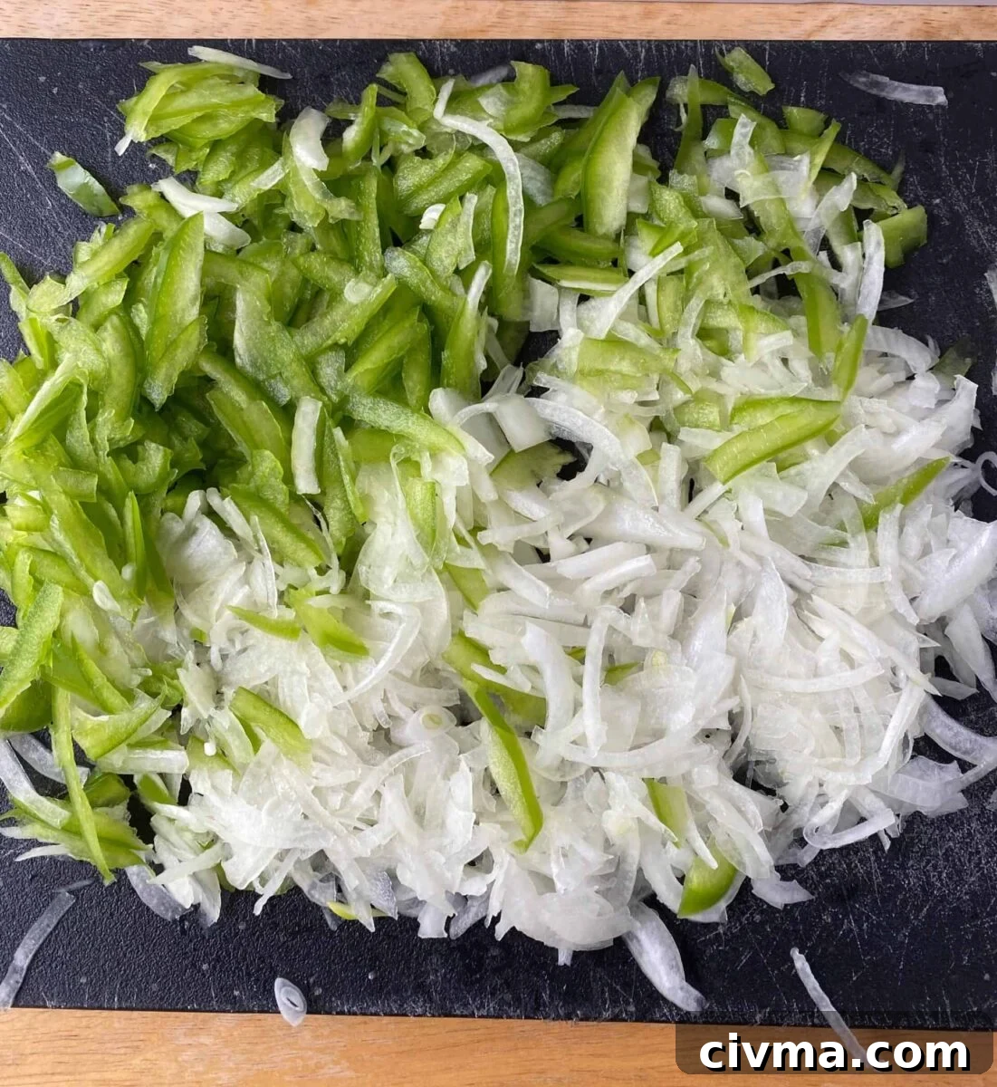 Philly Cheesesteak Bites Recipe 7 Sliced green pepper and onion on a cutting board.