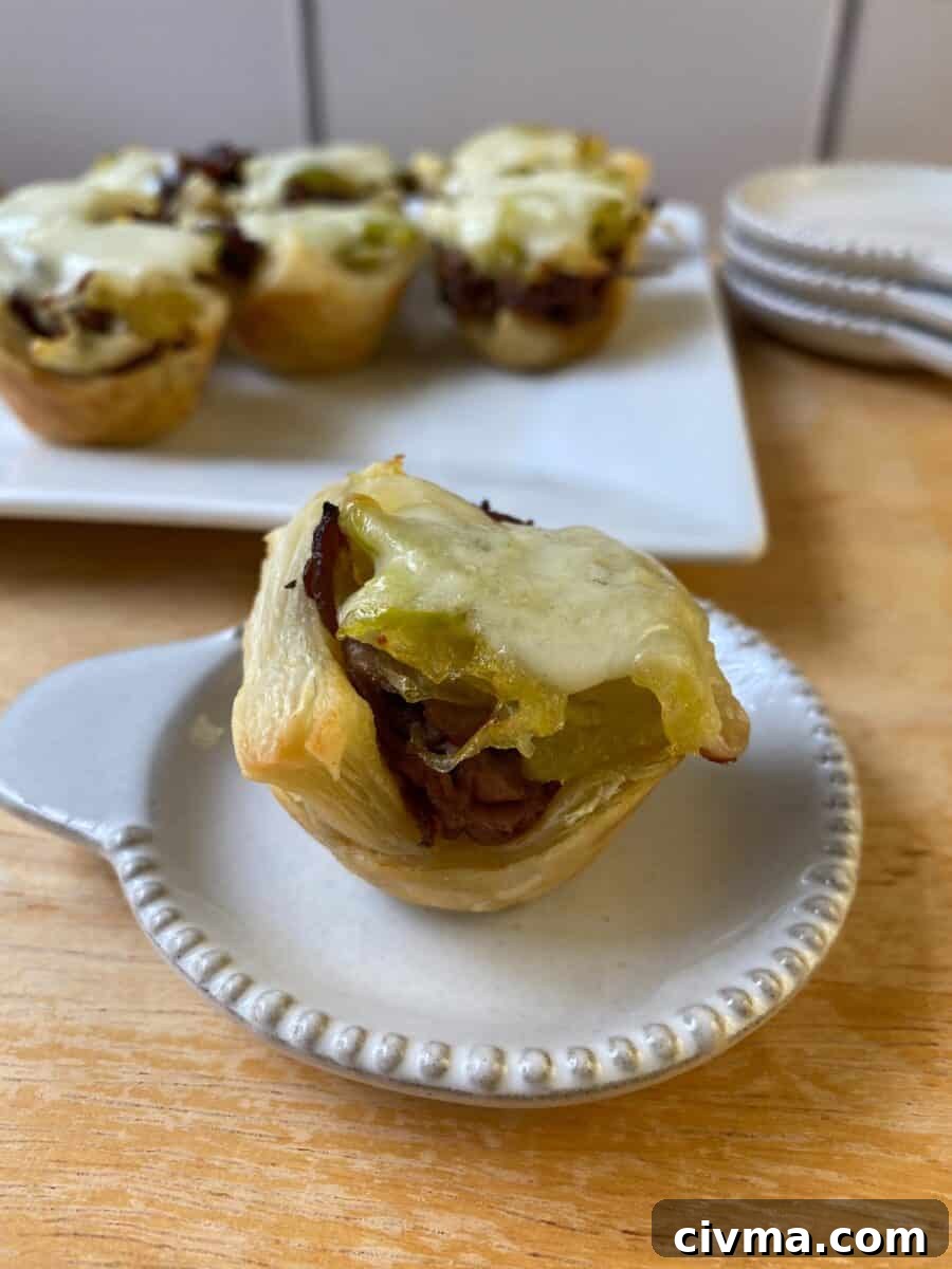 Philly Cheesesteak Bites Recipe 9 A Philly Cheesesteak Bite on a small plate, with a larger plate in the background and additional bites on display.