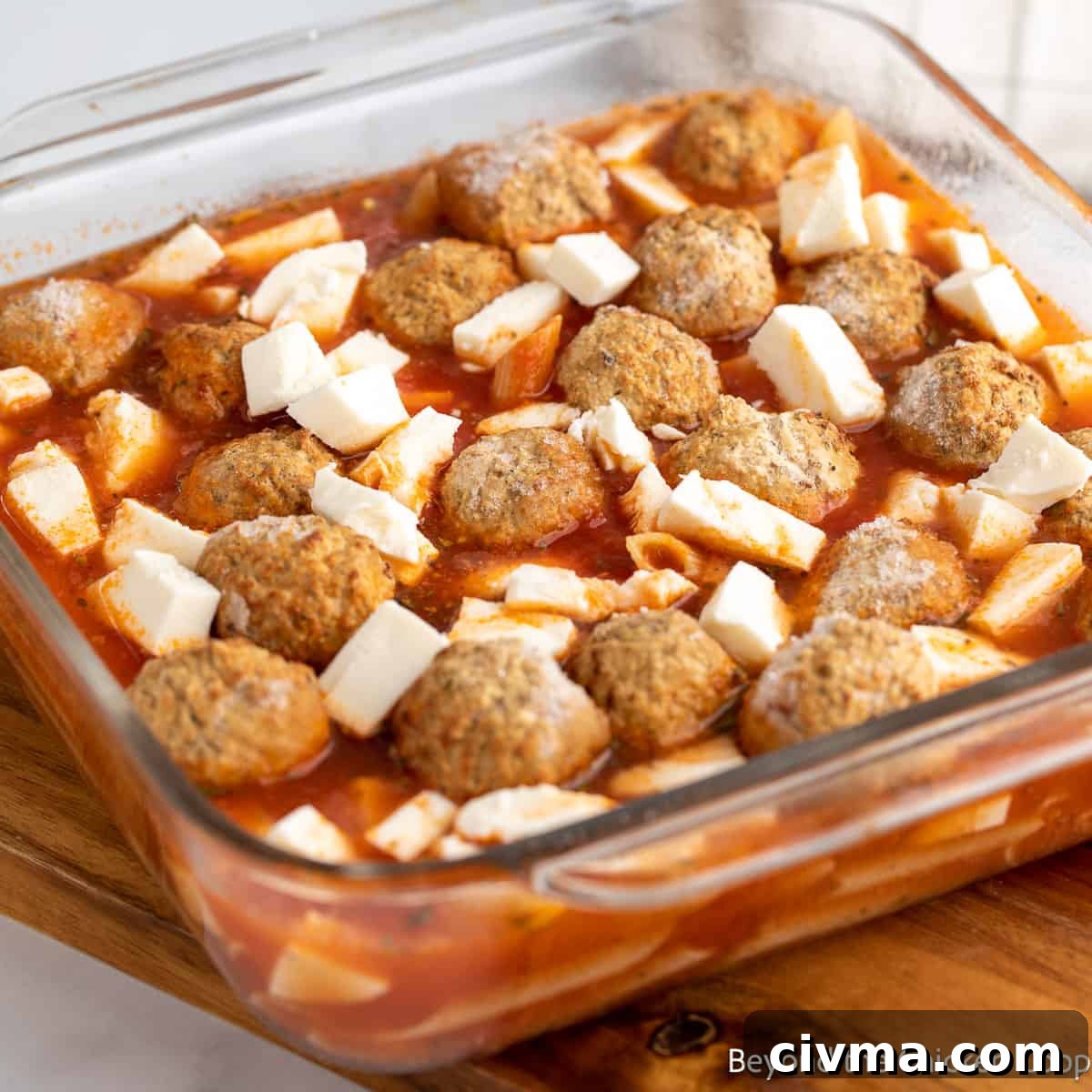 Making a pasta casserole with meatballs and mozzarella cheese.