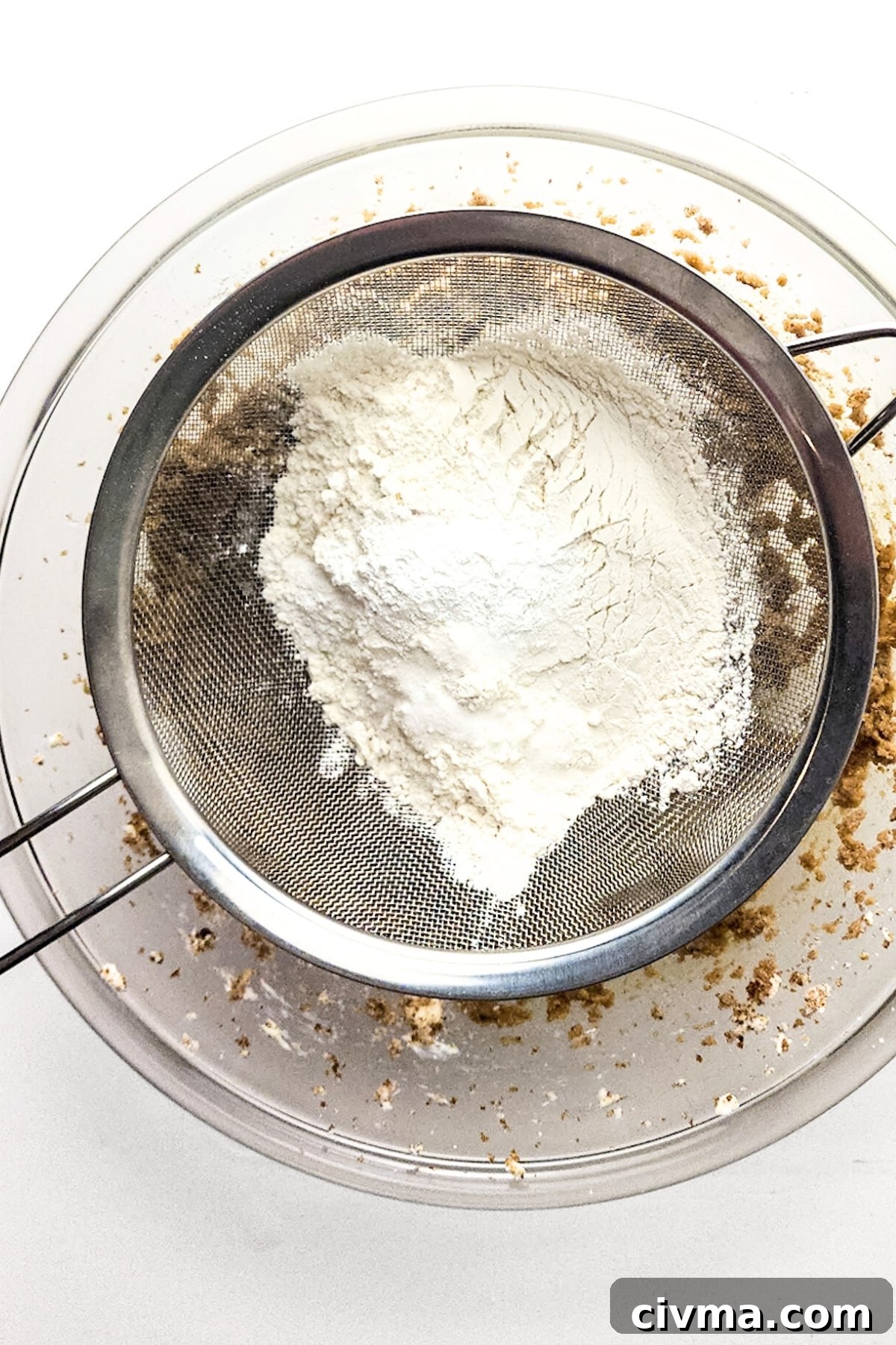 Sifting flour mixture into bowl.