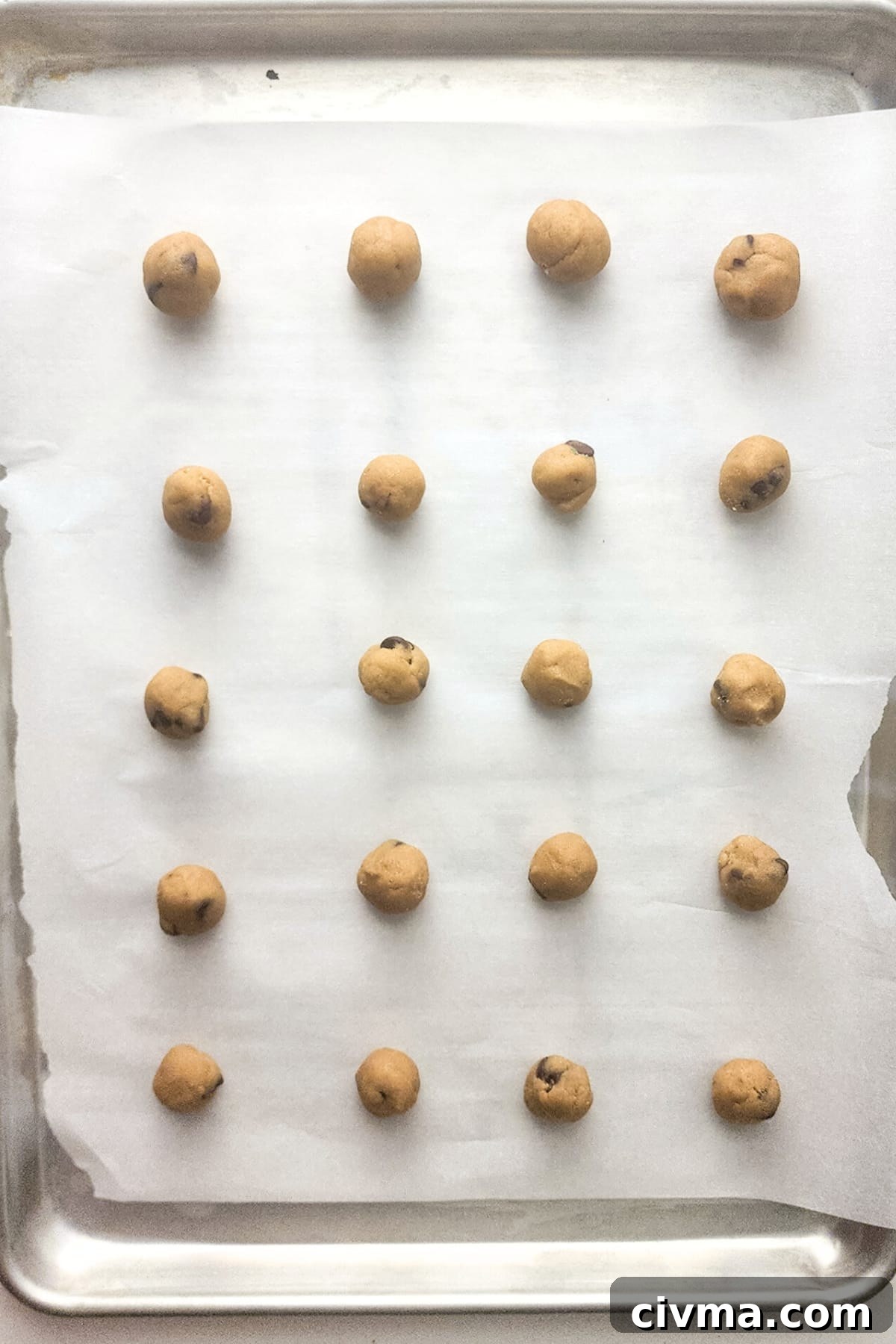 Cookie dough balls on parchment-lined cookie sheet.