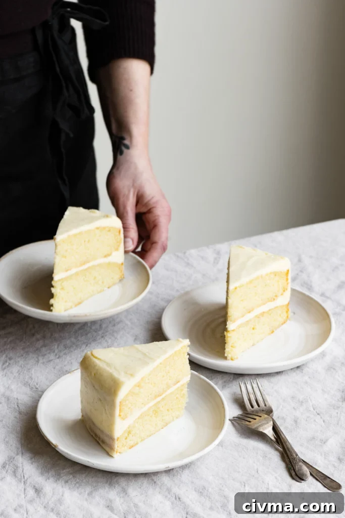A person's hand taking a plate with a cake slice off a table next to two other cake slices.