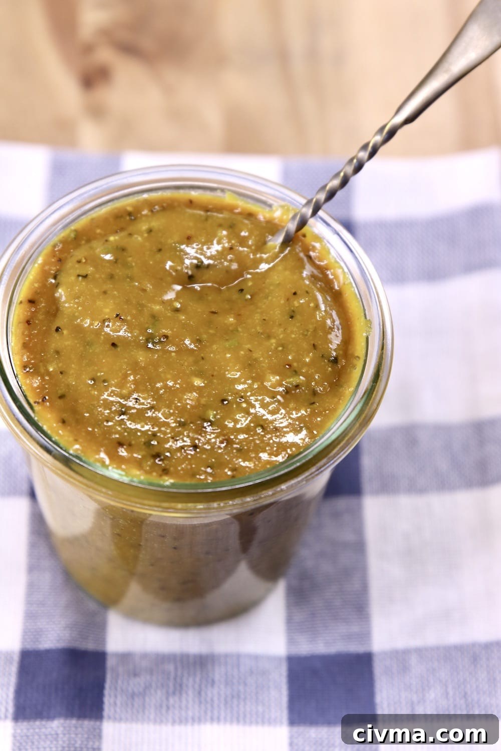Rosemary Mustard Sauce for grilling chicken & Pork Jar of Rosemary Mustard Sauce with a spoon sitting on a blue stripe towel