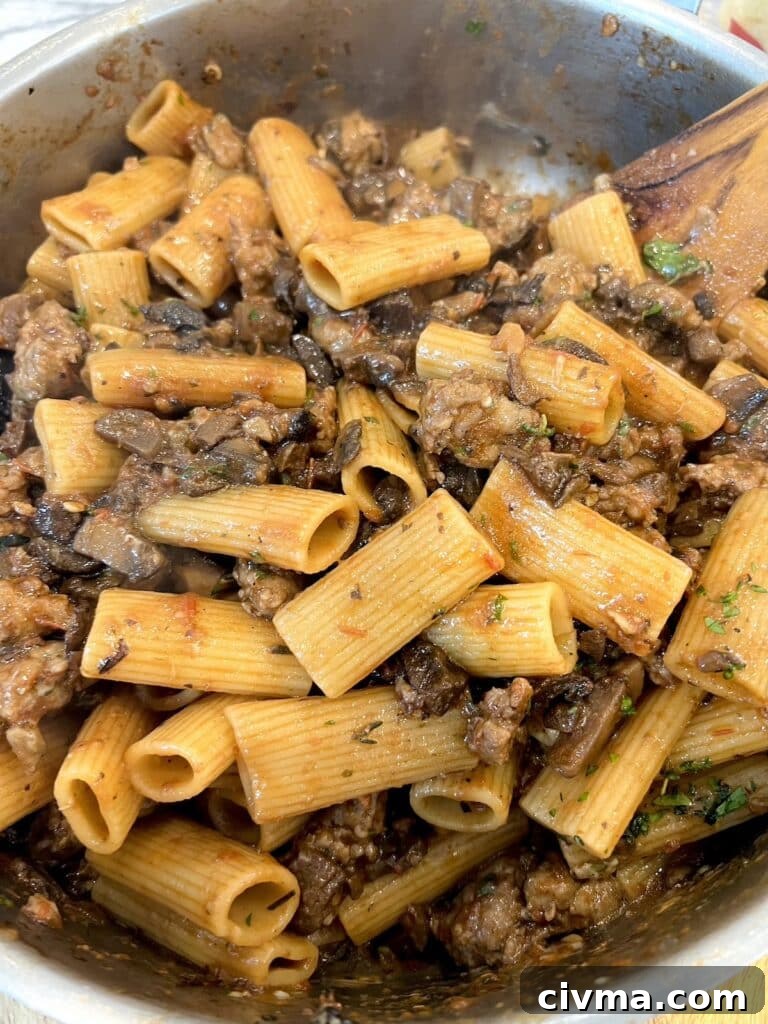 Rigatoni Boscaiola Recipe: Creamy Mushrooms and Sausage 3 Finished rigatoni boscaiola in pan with wooden spoon.