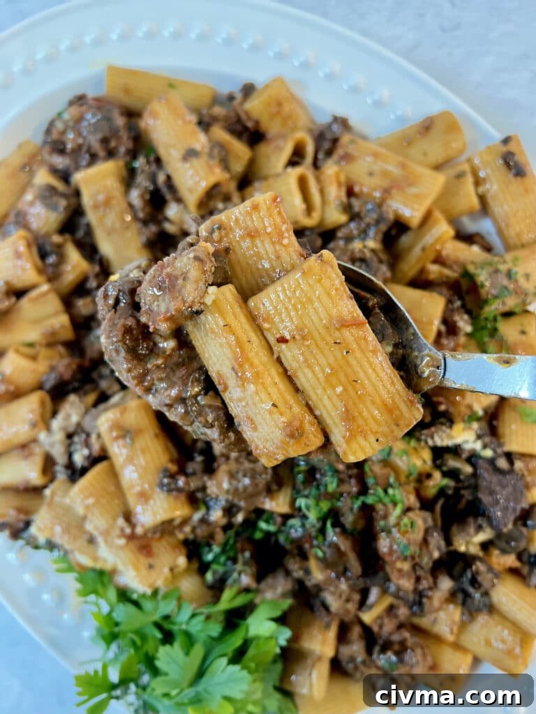 Rigatoni Boscaiola Recipe: Creamy Mushrooms and Sausage 7 A couple pieces of rigatoni boscaiola on large spoon over platter of pasta.