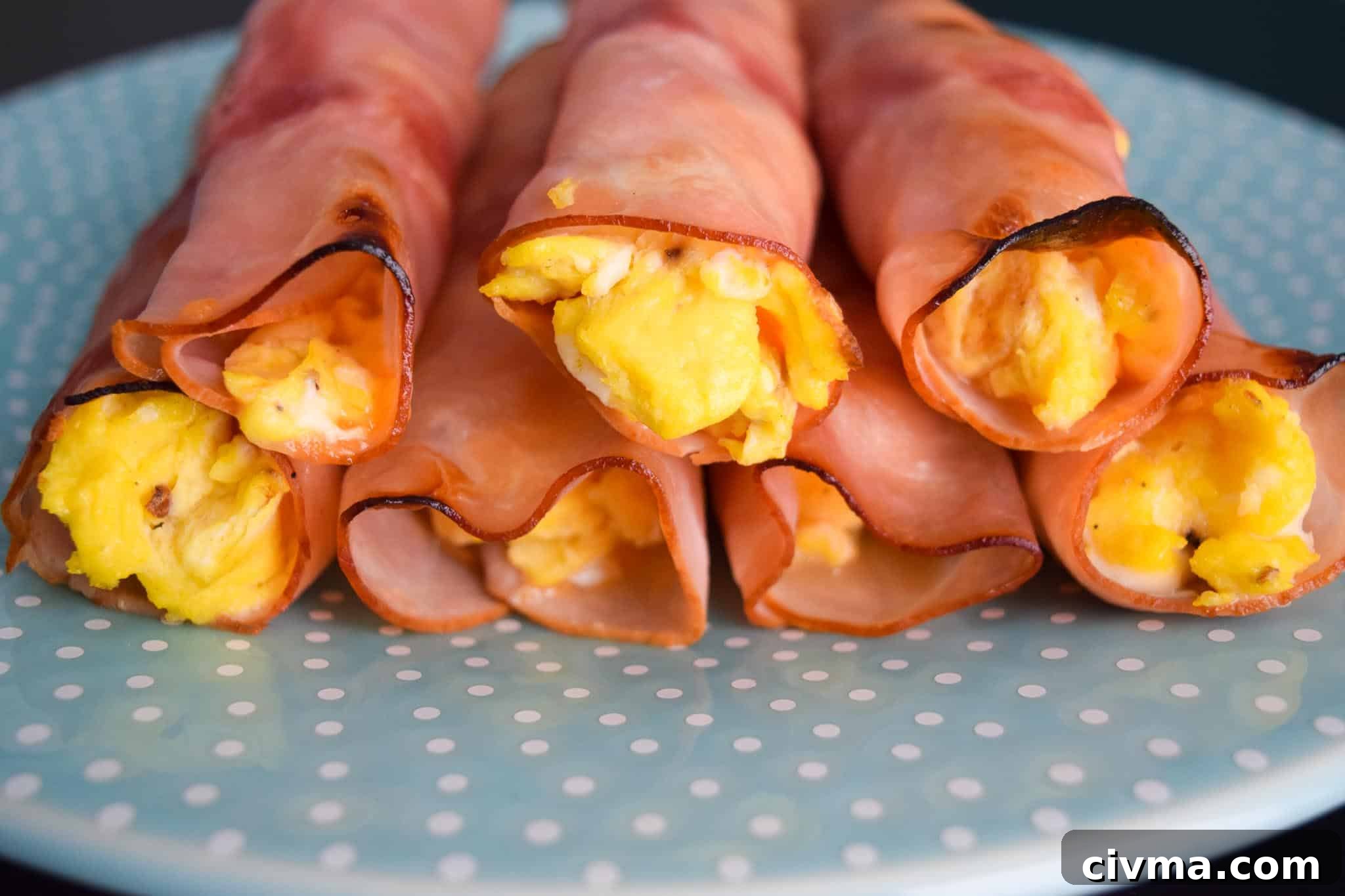 Ham Egg and Cheese Roll Ups Recipe 3 Ham Egg and Cheese Roll-Ups stacked on blue plate close up