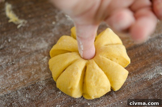 Poke the hole in the center of dinner roll dough using a finger.