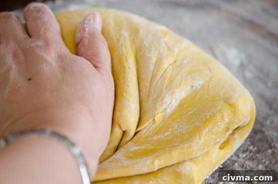 Pumpkin dinner roll dough kneaded by hand on the floured surface.