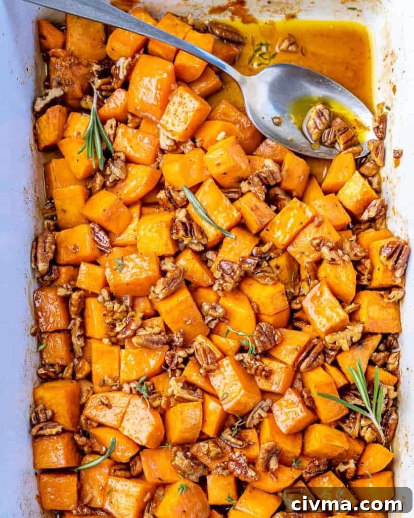 Top down view roasted sweet potatoes in a baking dish with a spoon.