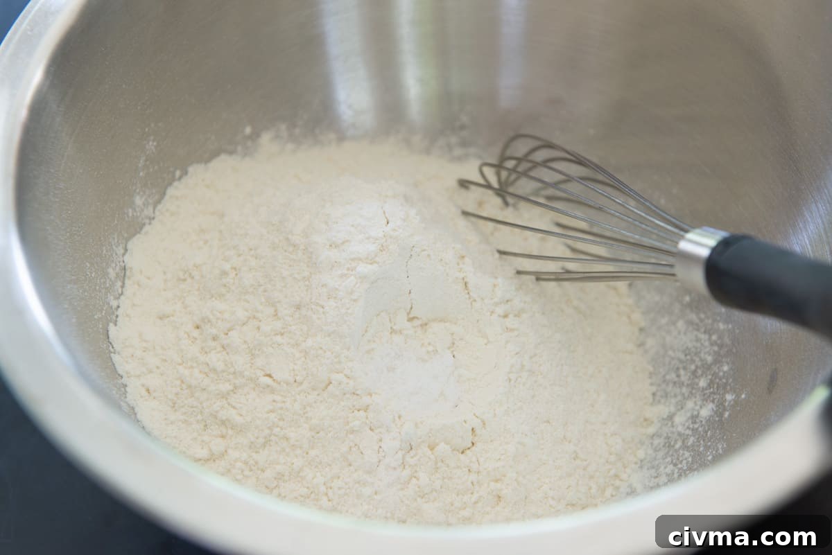 The dry ingredients in a stainless steel mixing bowl with whisk