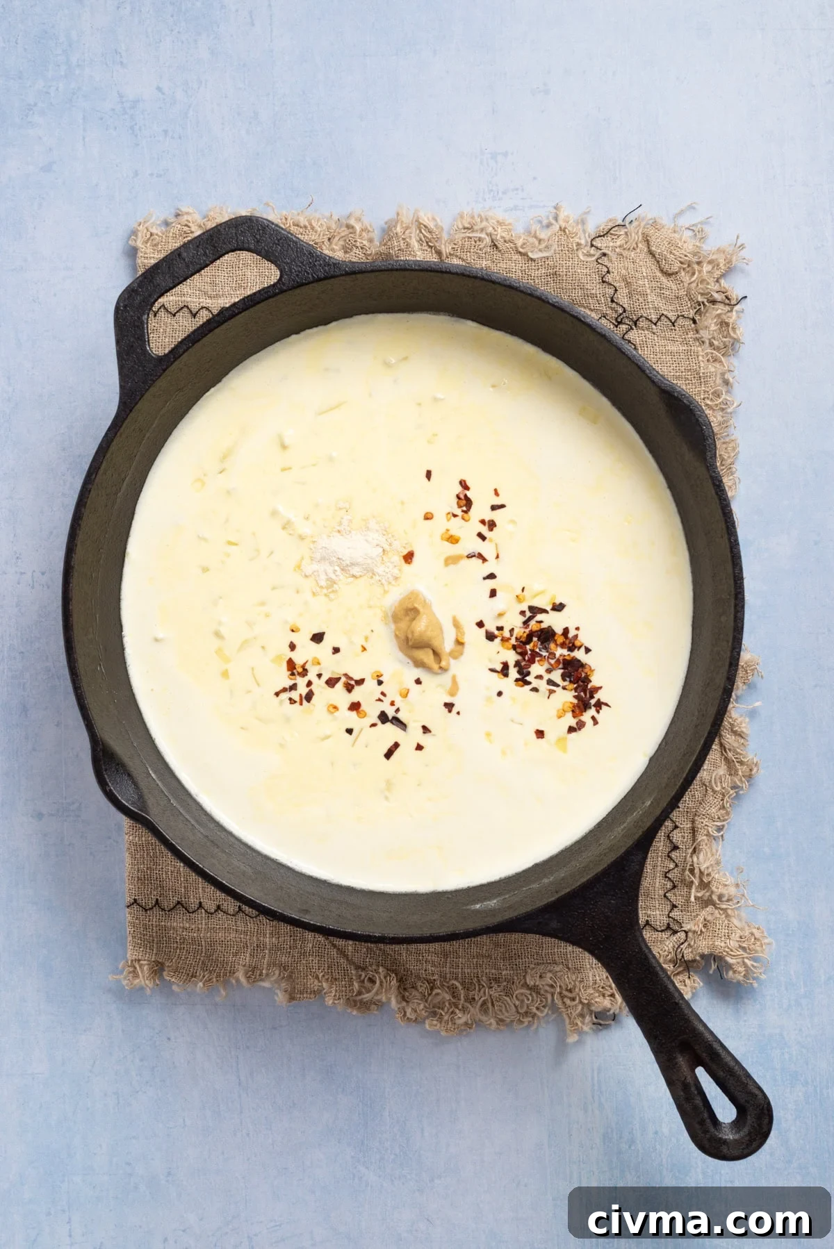 An image of heavy cream in a skillet, and adding spices to it.