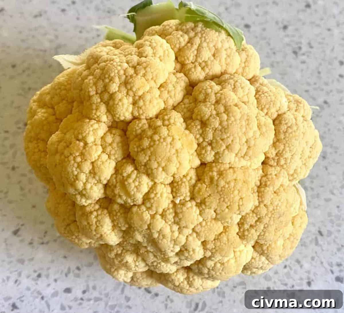 A head of cauliflower for vegan cauliflower recipes on a cutting board.
