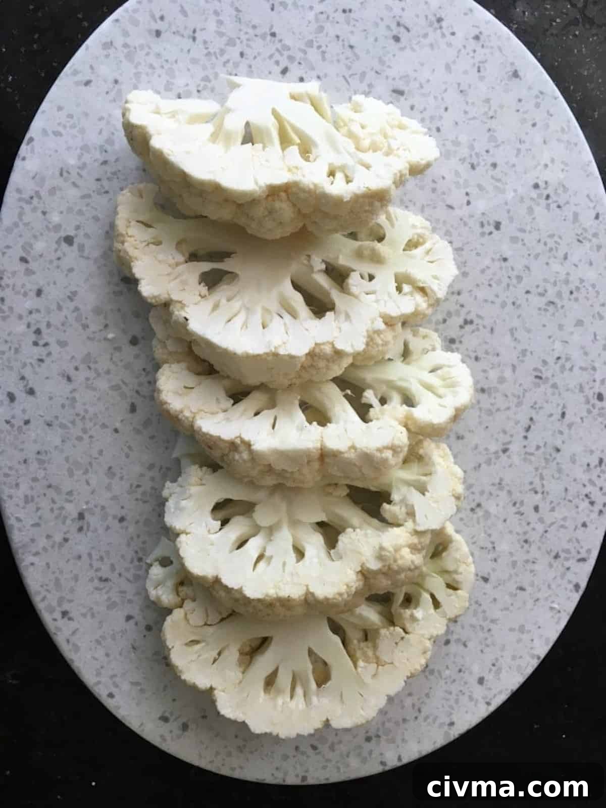 A head of cauliflower sliced into five cauliflower steaks.
