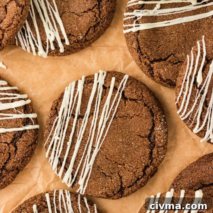 overhead shot of baked Double Molasses Gluten Free Ginger Cookies that have been drizzled with white chocolate on top of brown parchment paper