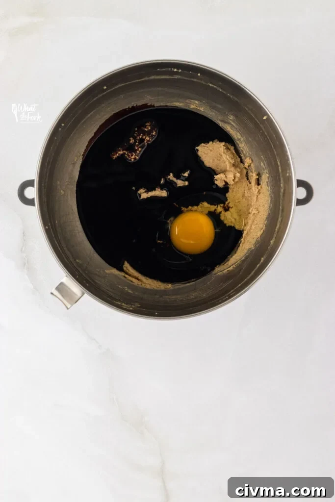 molasses and egg added to beaten butter and sugar in a silver stand mixer bowl