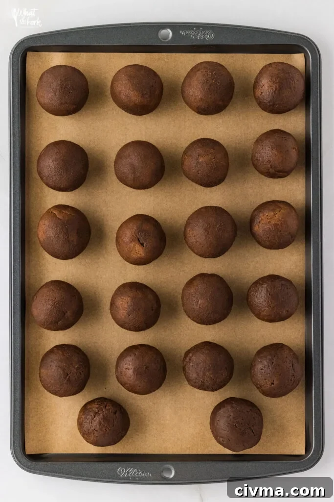 gluten free ginger cookie dough rolled into balls on a parchment paper lined cookie sheet