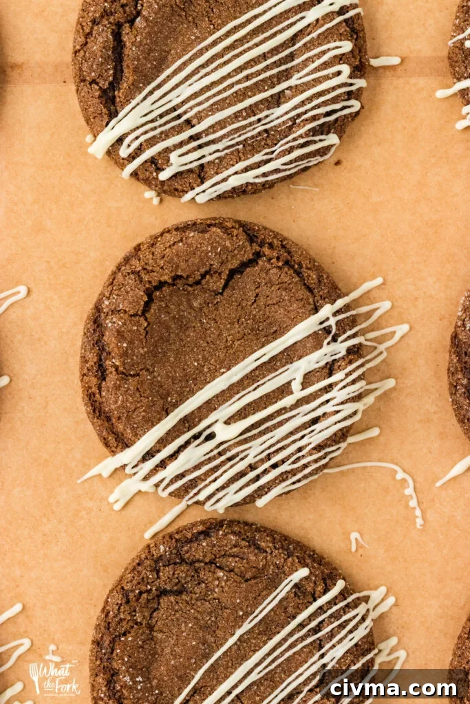 overhead shot of three gluten free ginger cookies on brown parchment paper that have been drizzled with white chocolate