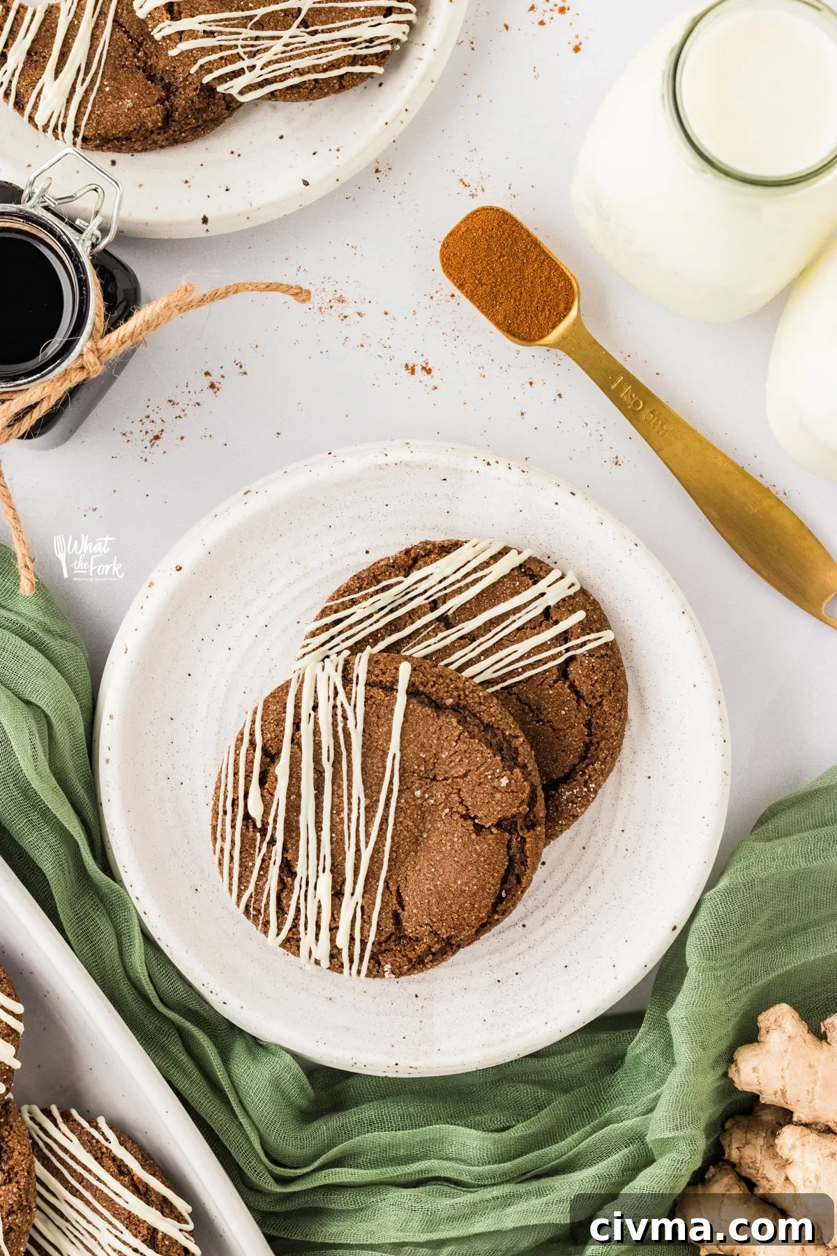 overhead photo of two Double Molasses Gluten Free Ginger Cookies drizzled with white chocolate on a small round white plate