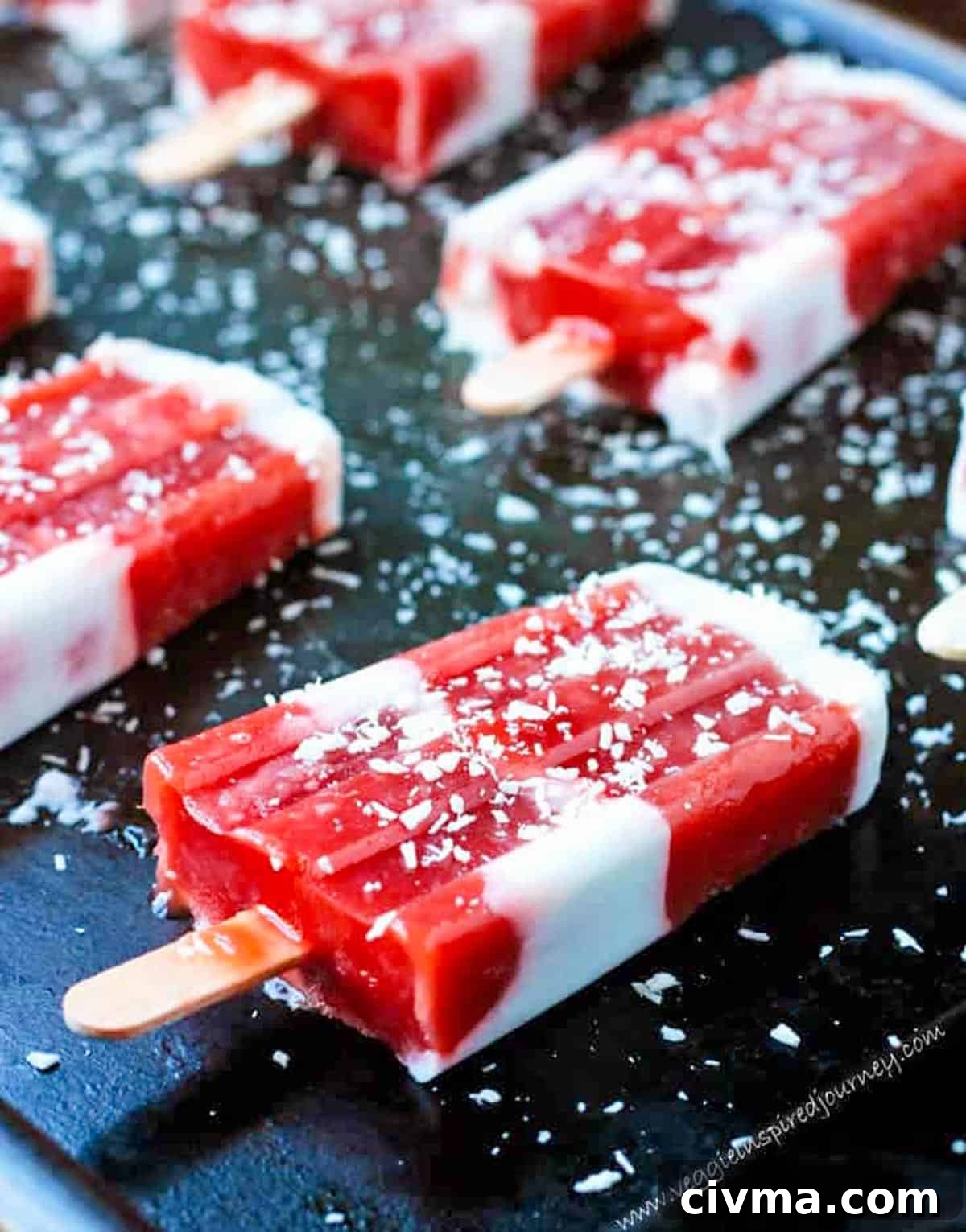 Red and white striped strawberry rhubarb coconut milk popsicles on a black background.
