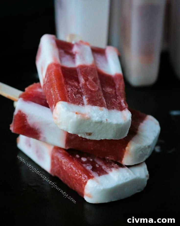 A stack of three Strawberry Rhubarb Coconut Milk Popsicles on a black tray.