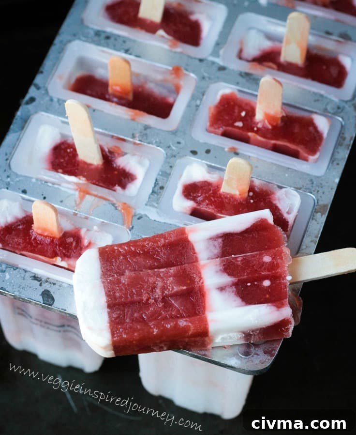 One Strawberry Rhubarb Coconut Milk Popsicle lying on top of a popsicle mold tray holding the remaining popsicles.