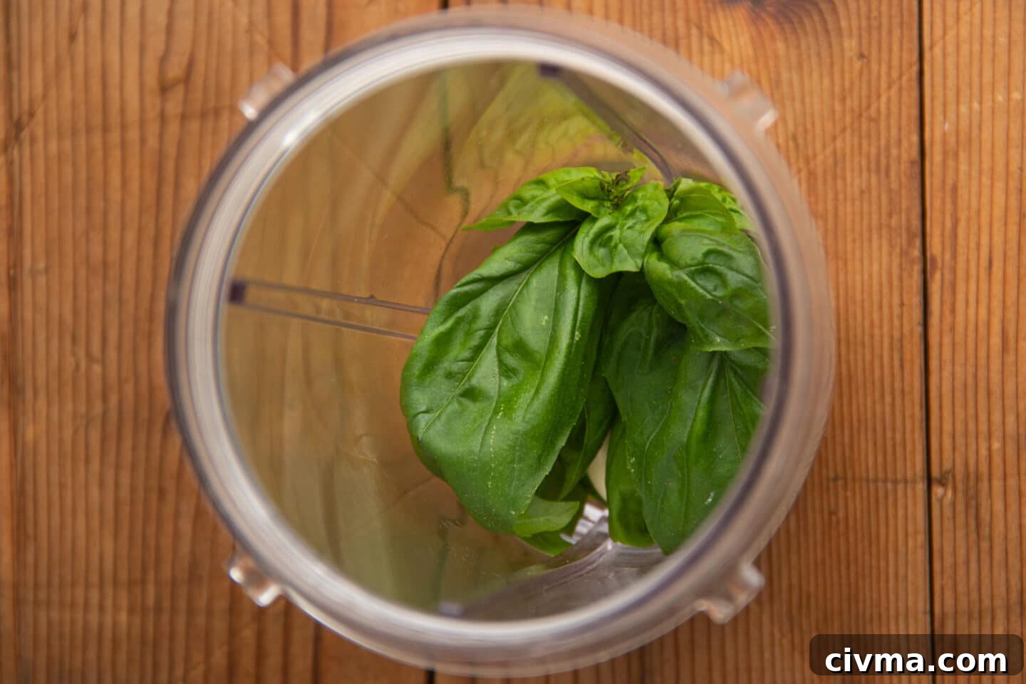 This is a picture of a blender filled with basil, garlic, parmesan and olive oil to make pesto.