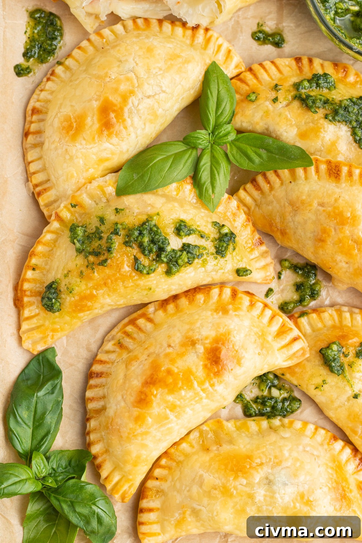This is a picture of baked caprese empanadas topped with pesto. 
