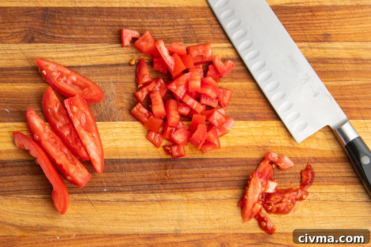 This is a picture of a cutting board and diced tomatoes with a knife. 