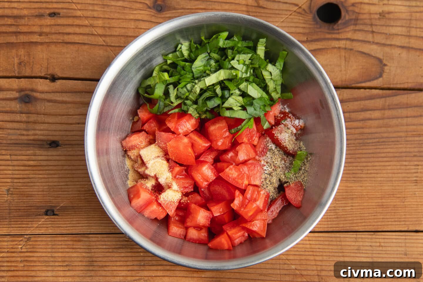 This is a picture of bowl with tomatoes, basil, and spices.