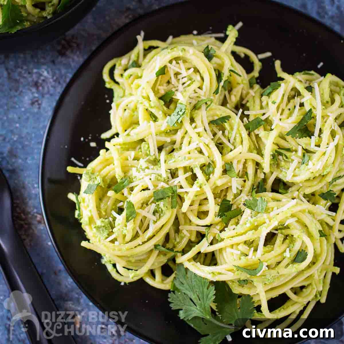 Green Spaghetti with Creamy Poblano Sauce 11 Overhead shot of green spaghetti garnished with parmesan and parsley leaves on a black plate.