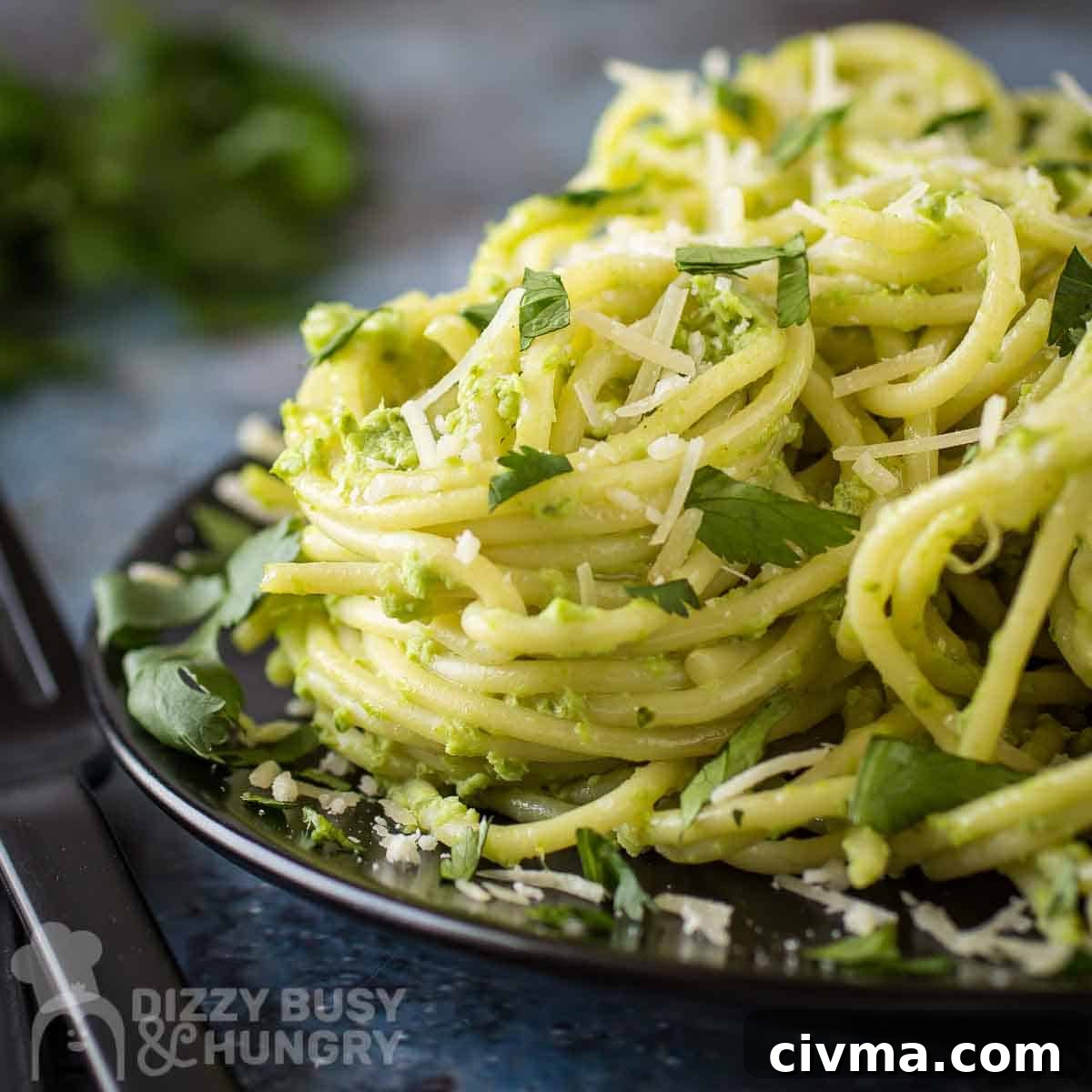 Green Spaghetti with Creamy Poblano Sauce 12 Close up side shot of green spaghetti garnished with parmesan and parsley leaves on a black plate.