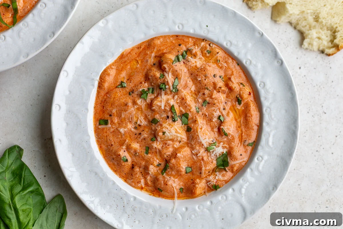 vodka sauce butter beans in a white bowl topped with basil and parmesan cheese