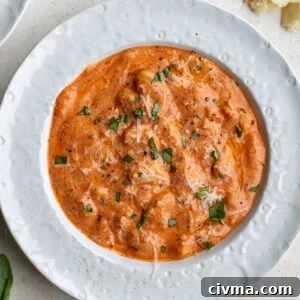 vodka sauce butter beans in a white bowl topped with basil and parmesan cheese